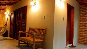 A wooden bench in a hallway with a brick wall and wooden shutters.