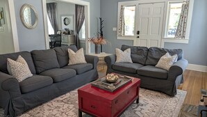A living room with two grey sofas, a red coffee table, and patterned rugs. - This Suite Old House (Cocoa)