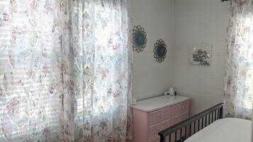 Ein Schlafzimmer mit blumigen Vorhängen, einem rosa Schminktisch, einem Bett und Wanddekorationen.