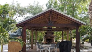 A covered outdoor seating area with a grill and chairs. - This Suite Old House (Cocoa)