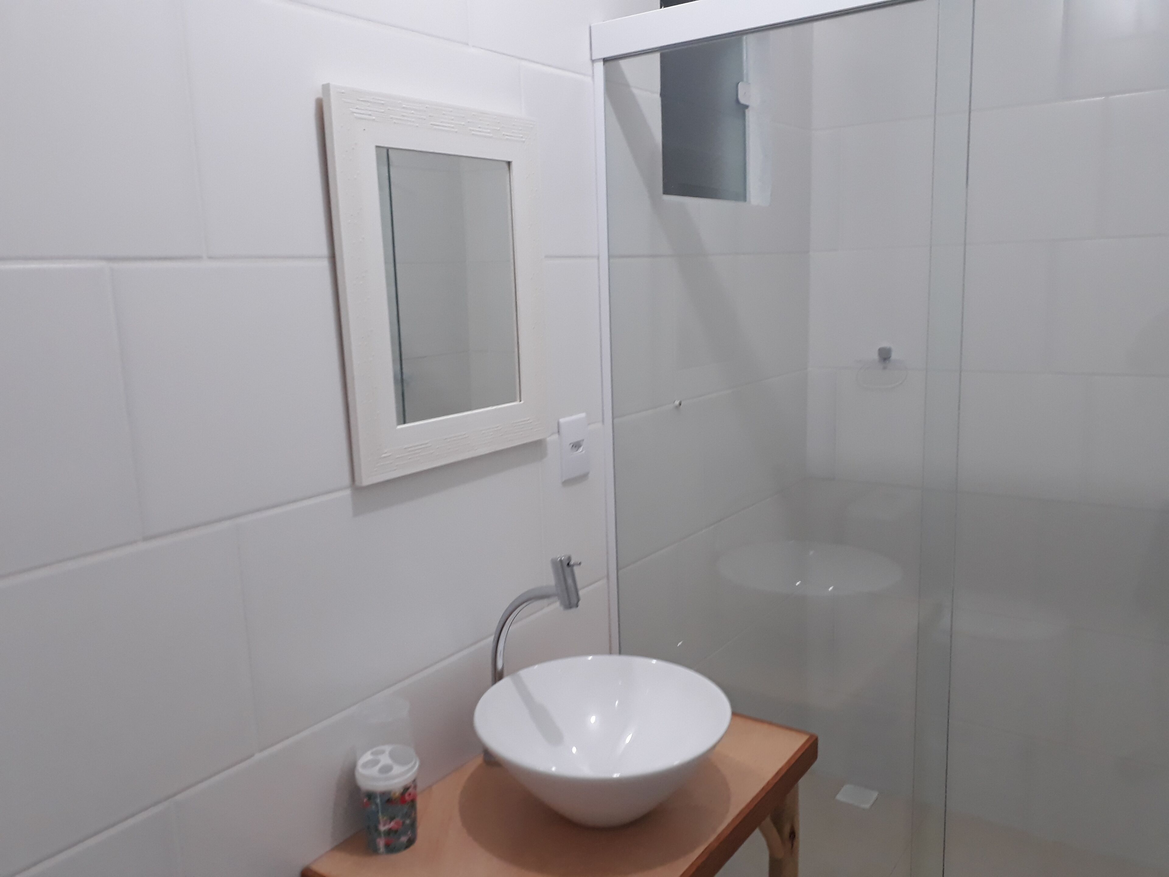 Un bagno con un lavandino bianco, uno specchio e cabina doccia.
