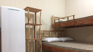 Una cama litera con escalera de madera, un refrigerador blanco y una pequeña estantería de madera.