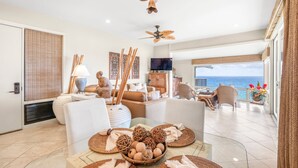 Un vaste espace de vie avec un balcon donnant sur la mer, aménagé avec des canapés modernes et une table à manger.
