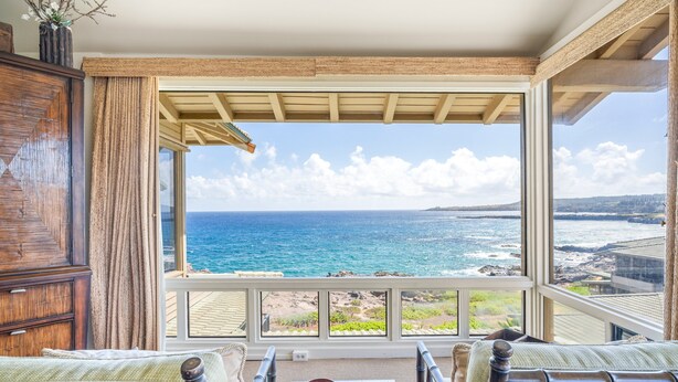 Une pièce avec vue sur l’océan, un meuble en bois et deux chaises avec une table.