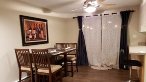 Un coin repas avec une table et des chaises en bois, un ventilateur de plafond et un tableau encadré au mur.