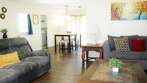 Ein Wohnzimmer mit zwei grauen Sofas, einem Couchtisch mit einer Pflanze und einem Gemälde an der Wand.