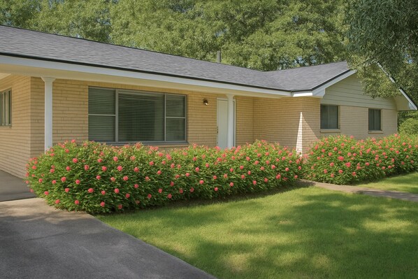A single-story house with a brick exterior, a covered porch, and a well-maintained lawn with pink flowering bushes. - 3/2 on 1 acre on main road close to Casinos, Restaurants & Plants! (Lake Charles)