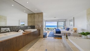Ett modernt hotellbadrum med ett stort badkar, en separat dusch och en tvättställsmöbel med en stor spegel.