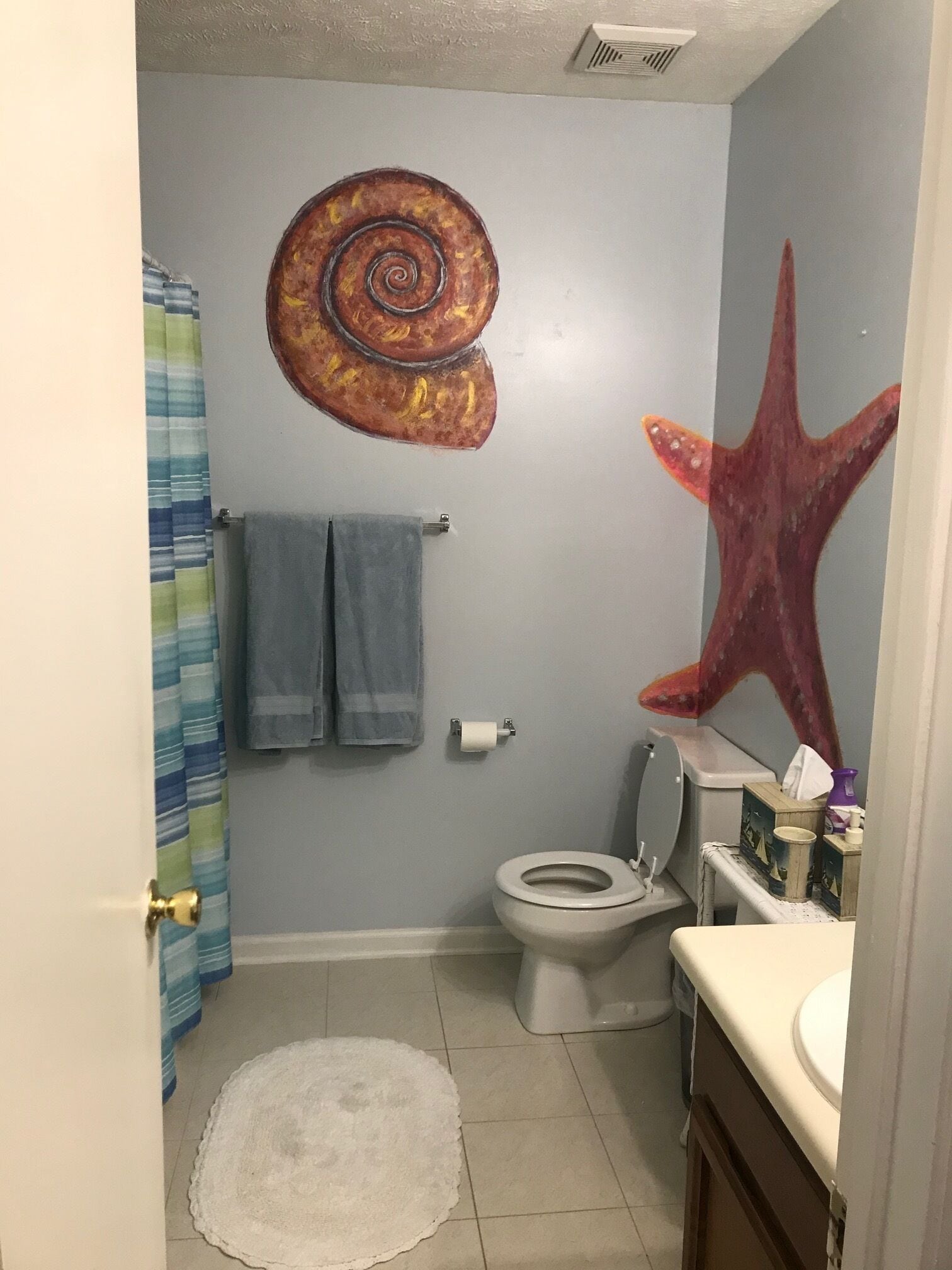 A bathroom with a toilet, sink, and a towel rack.