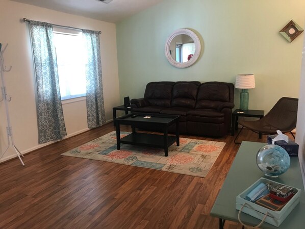 A living room with a brown leather sofa, a coffee table, a lamp, a chair, and a globe on a side table.