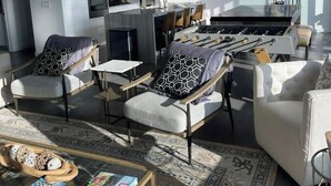 Een moderne woonkamer met een bank, fauteuils, een salontafel en een vloerkleed.