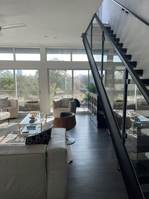 A modern living room with a staircase, large windows, and a view of the outdoors. - Luxury Penthouse 2 Blocks | Near UT Stadium (Austin)