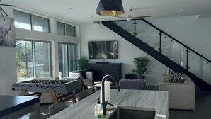 Een moderne keuken met een marmeren aanrechtblad, een inbouwspoelbak en een groot raam met uitzicht op een stadsbeeld.