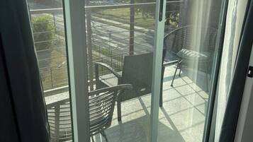 A balcony with a glass door, a chair, and a table.