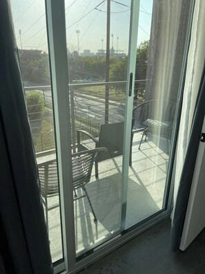 A balcony with a glass door, a chair, and a table.