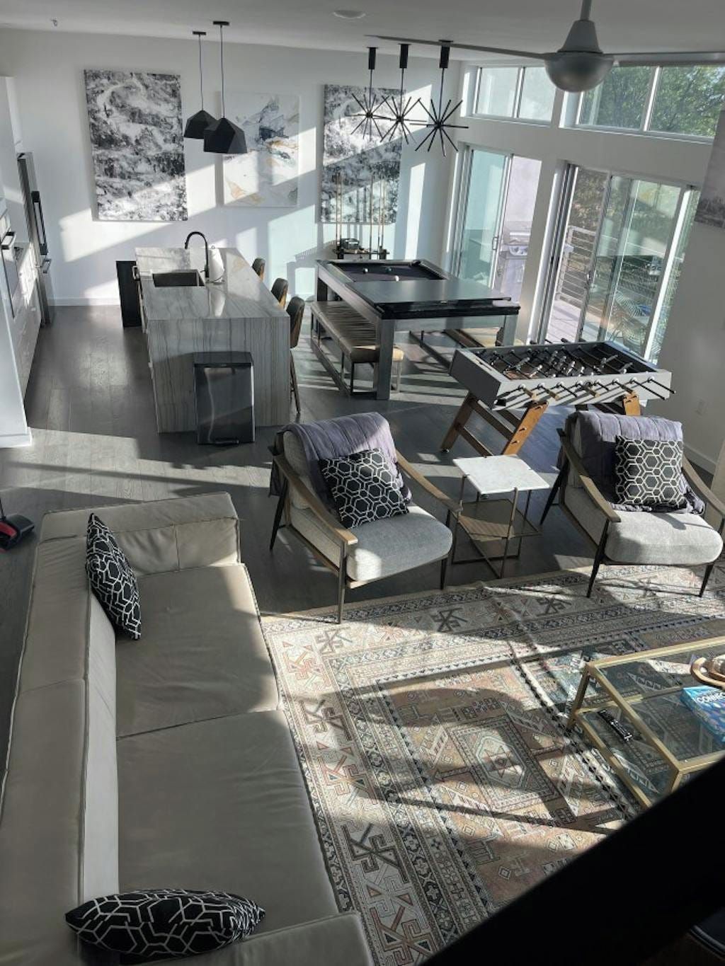 A modern living space with a sofa, chairs, a dining table, and a kitchen area.