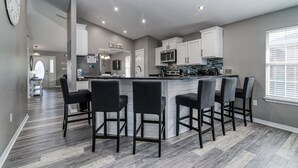 A modern kitchen with a central island, bar stools, and built-in appliances. - Private Pool! Walk to Beach! 3 Kings & Quad Bunk! (Miramar Beach)