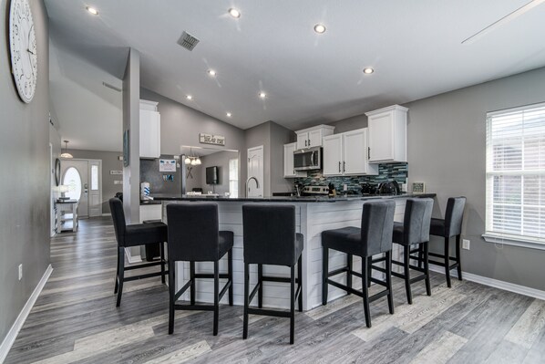 A modern kitchen with a central island, bar stools, and built-in appliances.