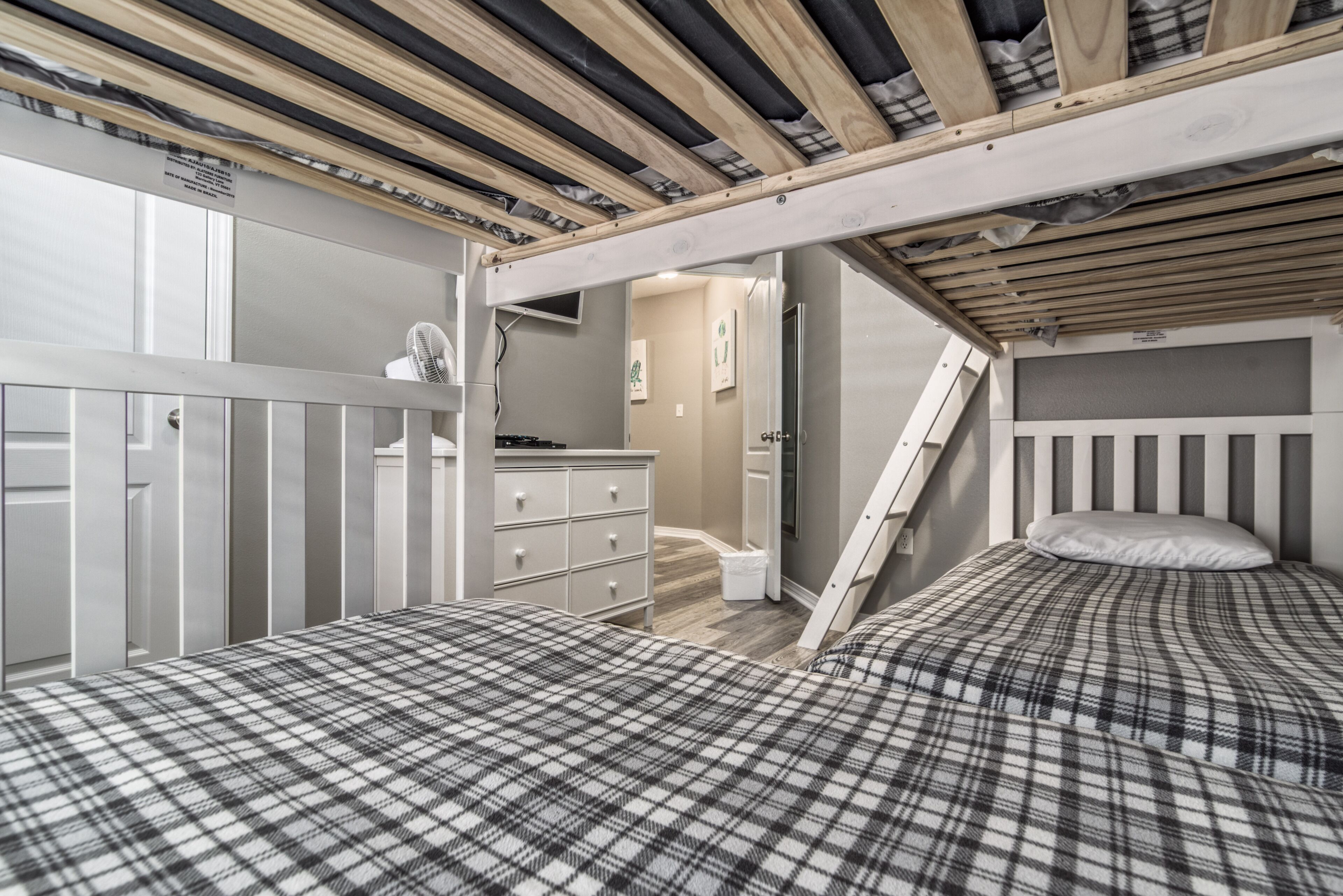Una habitación con dos camas, un aparador y una escalera que sube a un nivel superior.