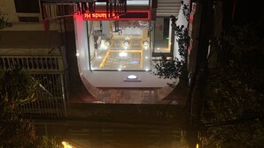 Un bâtiment orné d’une enseigne au néon sur laquelle on peut lire « HAND’S », et dont l’image se reflète dans l’eau.