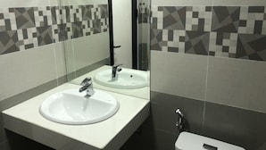 Une salle de bain avec un lavabo blanc, un miroir et des toilettes.