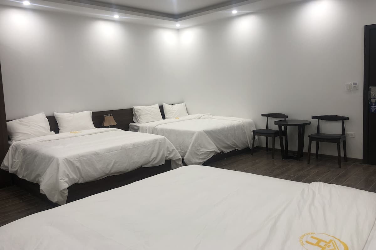 Una habitación de hotel con dos camas individuales, una mesita, dos sillas y una lámpara.