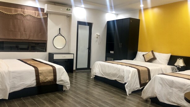 Une chambre d’hôtel avec trois lits, une armoire, un miroir et une porte.