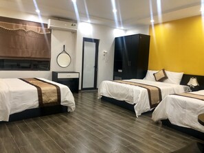 Ein Hotelzimmer mit drei Betten, einem Schrank, einem Spiegel und einer Tür.