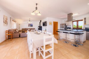 A modern kitchen with a dining area, a sofa set, and a TV.