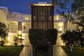A modern building with a central atrium, multiple balconies, and a well-lit entrance.