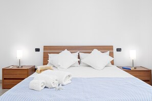 A neatly made bed with white linens, two bedside tables with lamps, and a book on the right table.