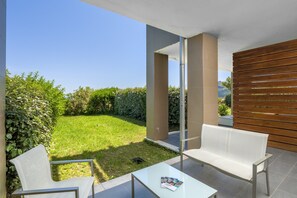 Une terrasse extérieure moderne avec un banc blanc, une table en verre et un magazine.