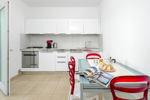 A modern kitchen with white cabinets, a gas stove, a coffee maker, and a dining table with chairs.
