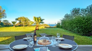 An outdoor dining table with a view of the sea, surrounded by greenery. - Spacious Apartment "Villa Marconi 6" with Sea View, Private Terrace & Garden (Golfo Aranci)
