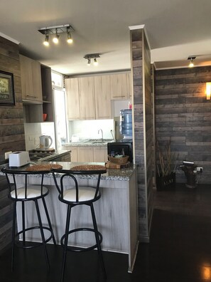 A modern kitchen with a central island, bar stools, and a built-in stove.