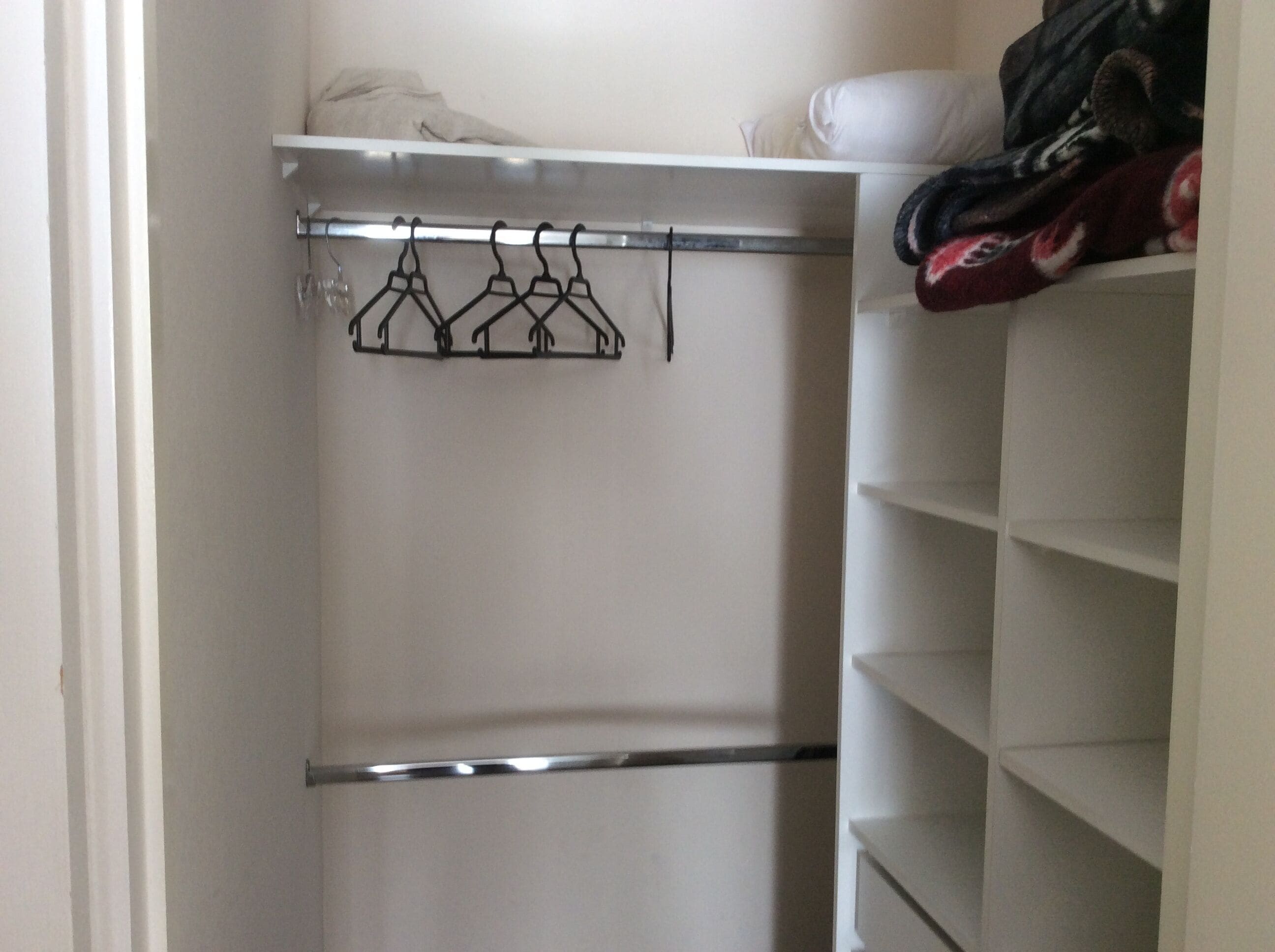 Ein Kleiderschrank mit Metallkleiderbügelstange und Regalen.