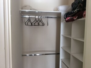 A closet with a metal hanger rack and shelves.