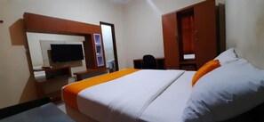 A hotel room with a bed, a desk, a chair, a TV, and a wardrobe. - Residence Duksina 2 by SHM (Depok)