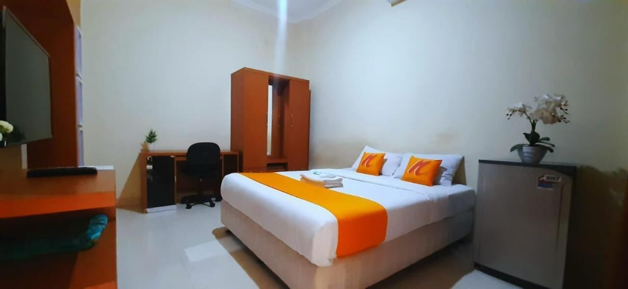 A hotel room with a bed, a desk, a wardrobe, and a refrigerator.