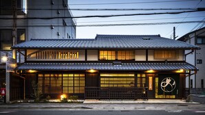 A traditional Japanese building with a tiled roof, a wooden facade, and a signboard.