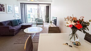 A modern living room with a sofa, coffee table, and a vase of flowers. - Apartments on Connor (Fortitude Valley)