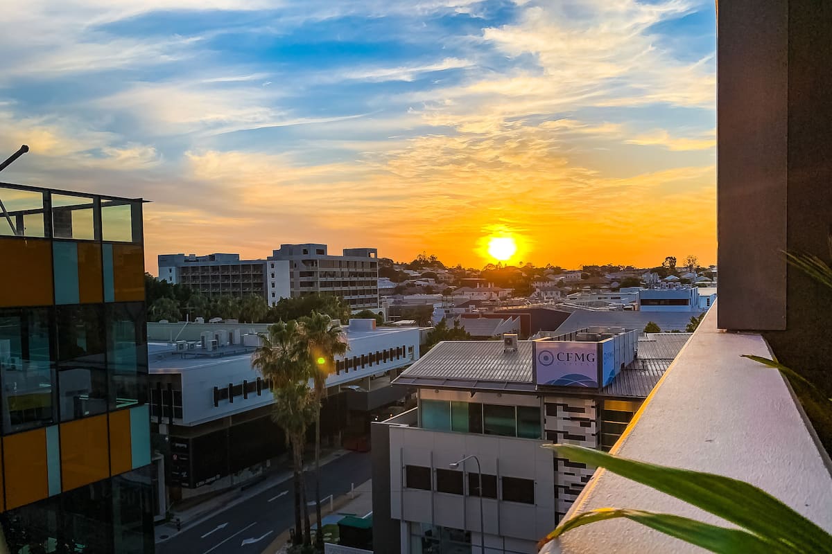 A cityscape with a sunset, modern buildings, and a palm tree.