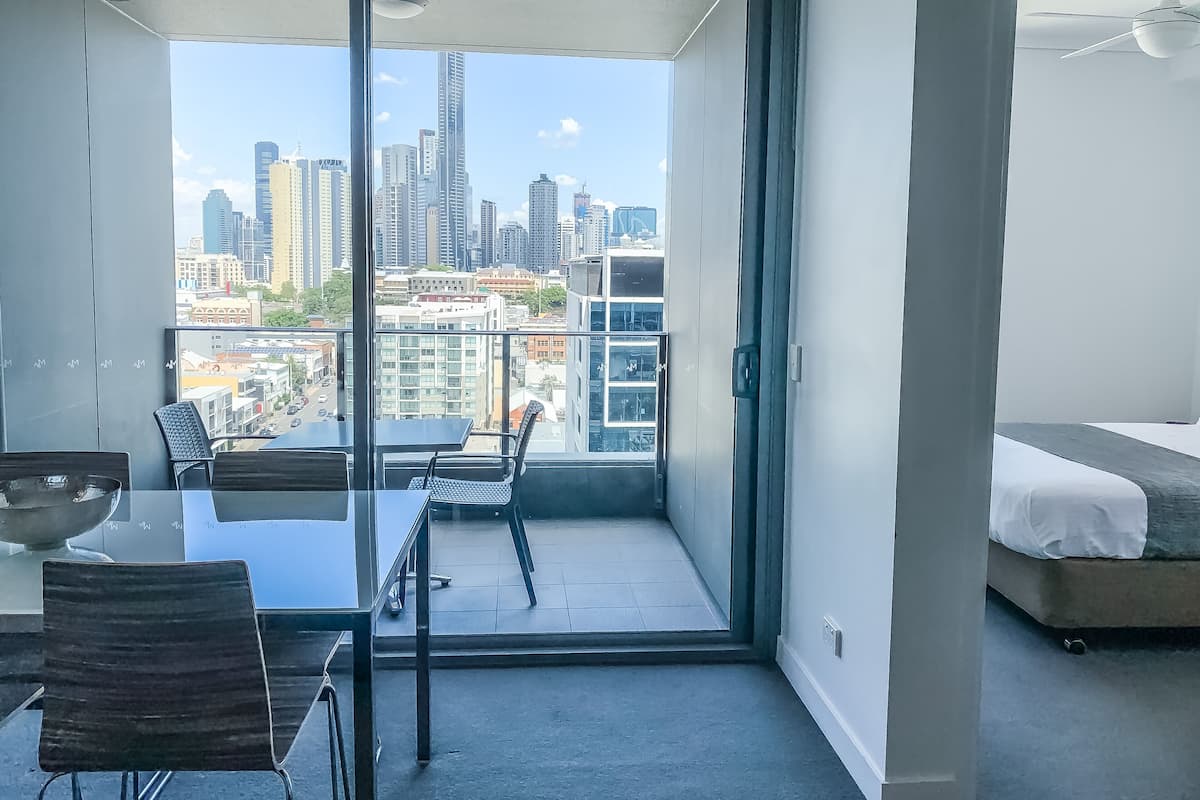 A modern apartment with a balcony, a dining area, and a bed.