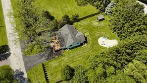 Vista aérea de una casa con un patio amplio, una zona cercada y un cobertizo pequeño.