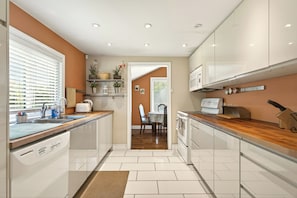 A modern kitchen with white cabinets, a built-in oven, and a dining area with a table and chairs.