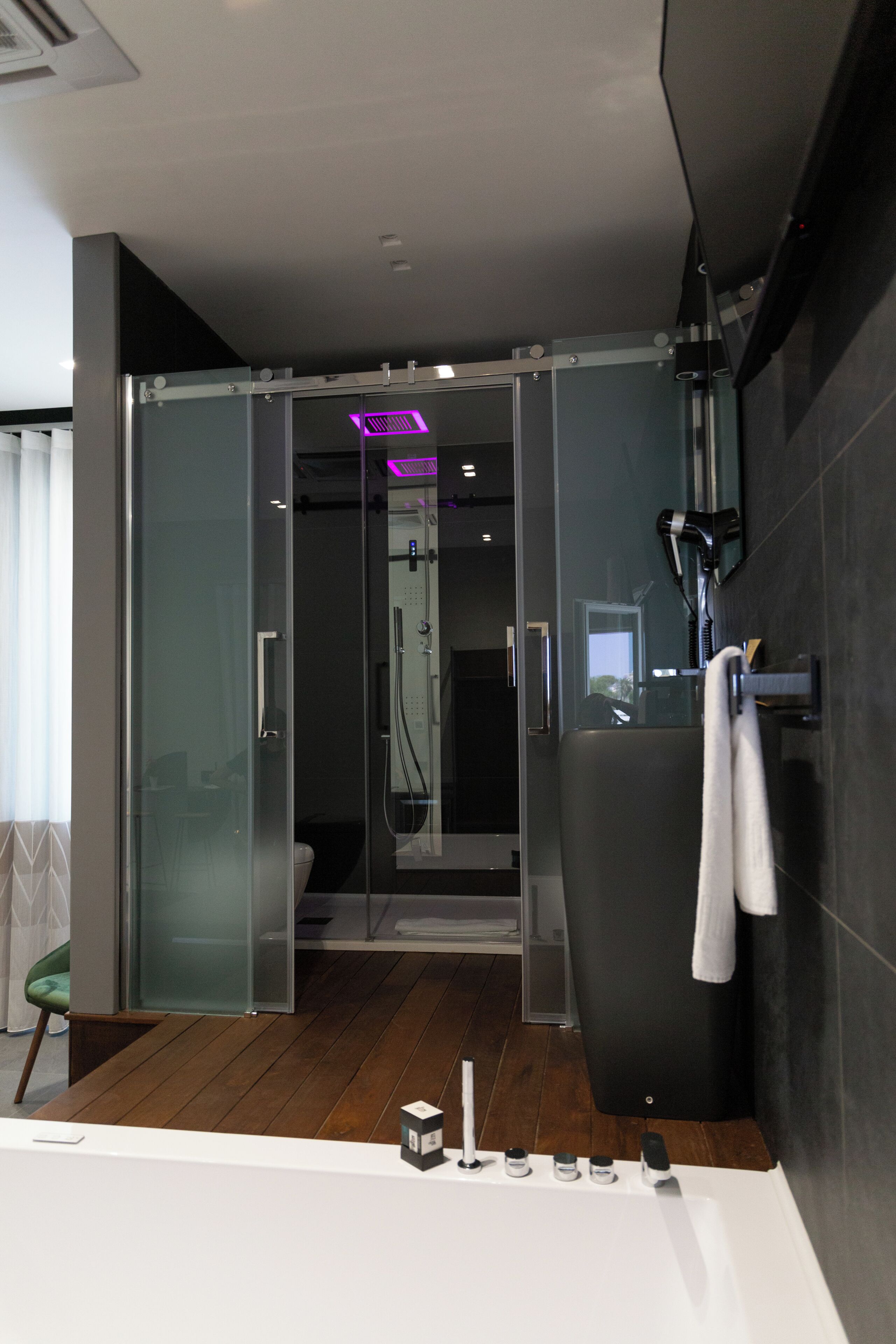 Un bagno moderno con cabina doccia in vetro, una vasca da bagno ampia e un porta asciugamani.