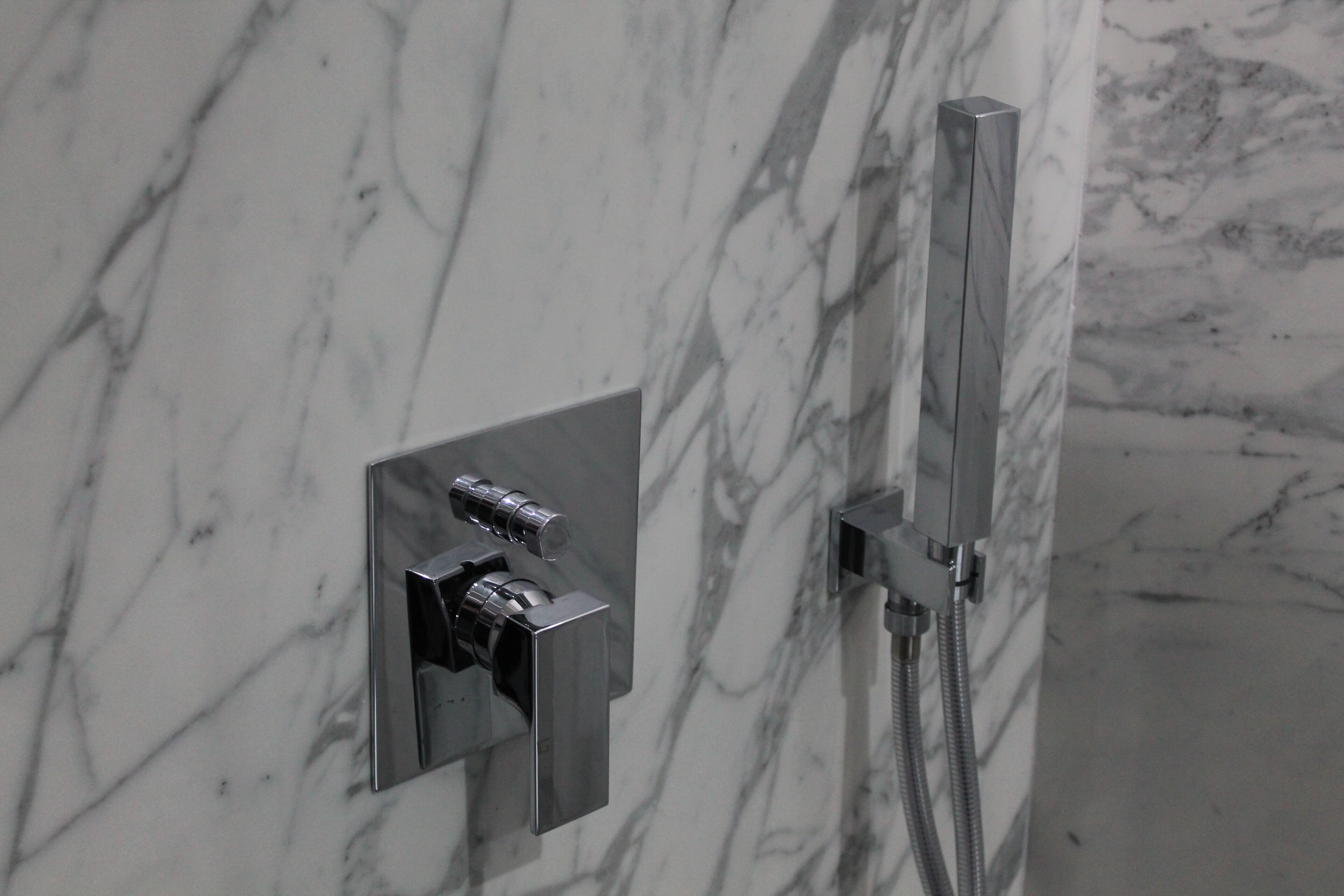 A bathroom with a marble wall and a modern shower system.