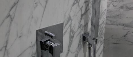A bathroom with a marble wall and a modern shower system.
