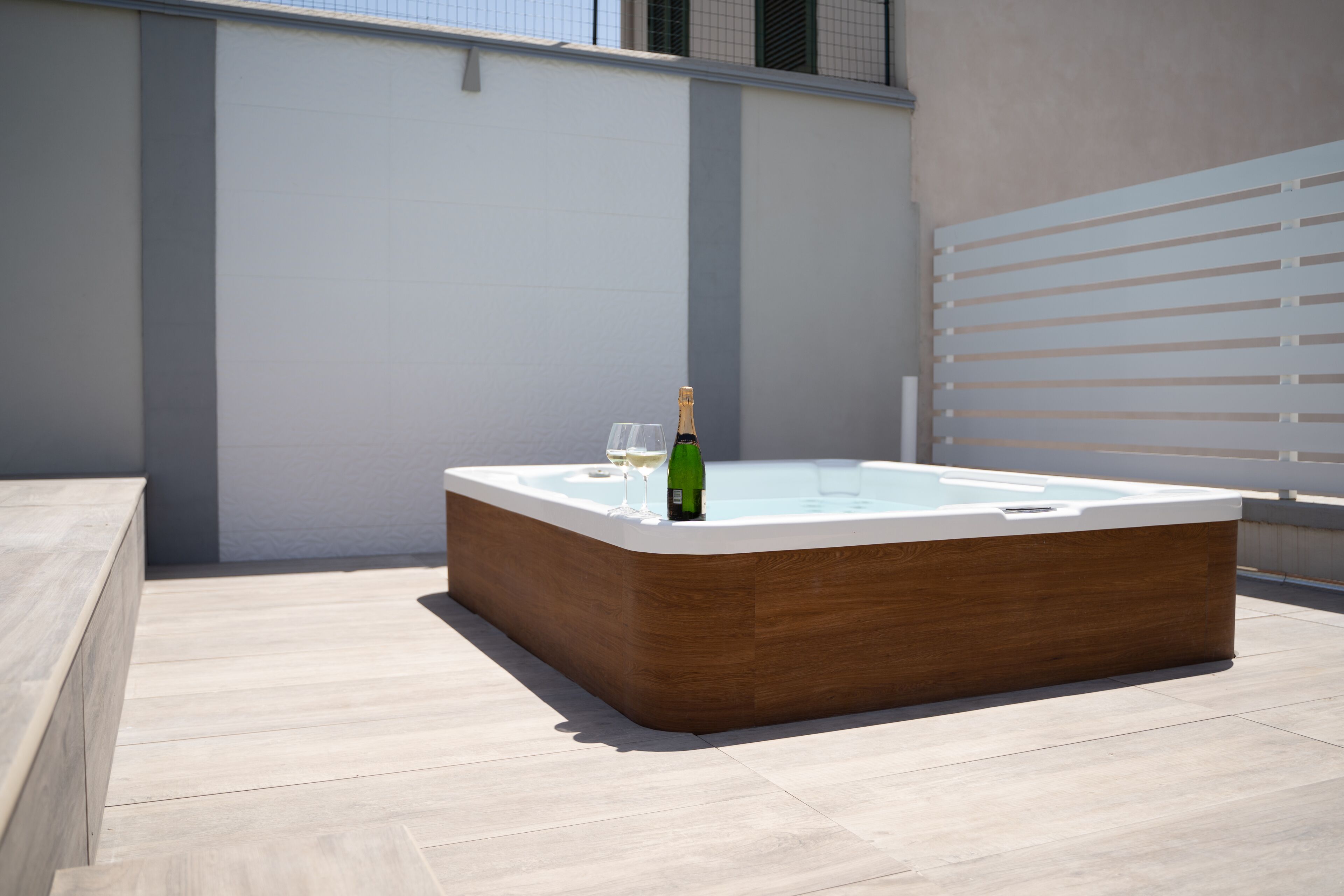 Tinaja exterior moderna con estructura de madera y tapa de vidrio, ubicada en un patio con baldosas.