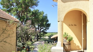 A courtyard with a pergola, potted plants, and a stone bench. - Le Clos Vitis - Chambres d'hôtes et gite (Violes)